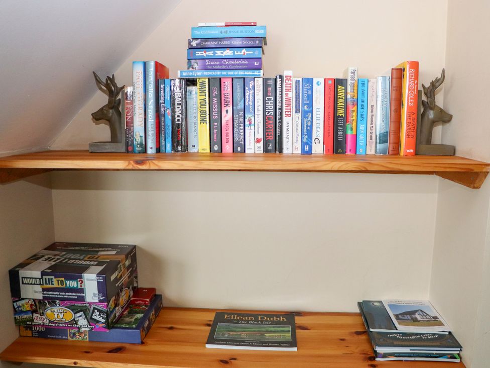 A study shelf with books and a board game at Otter Cottage Scarista near Leverburgh