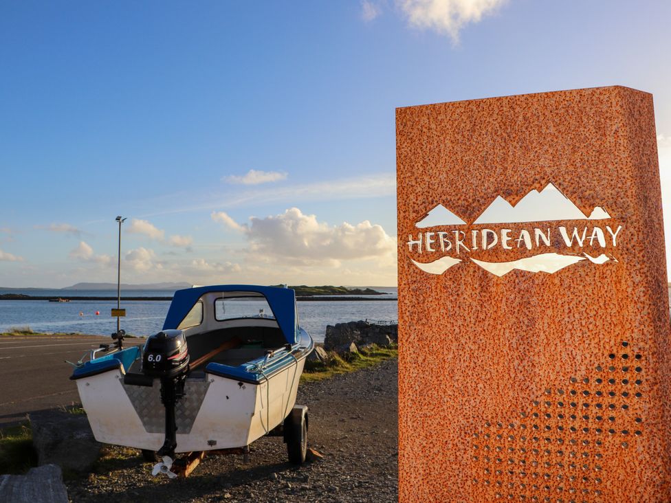 A boat with an outboard motor next to a sign for the Hebridean Way near water