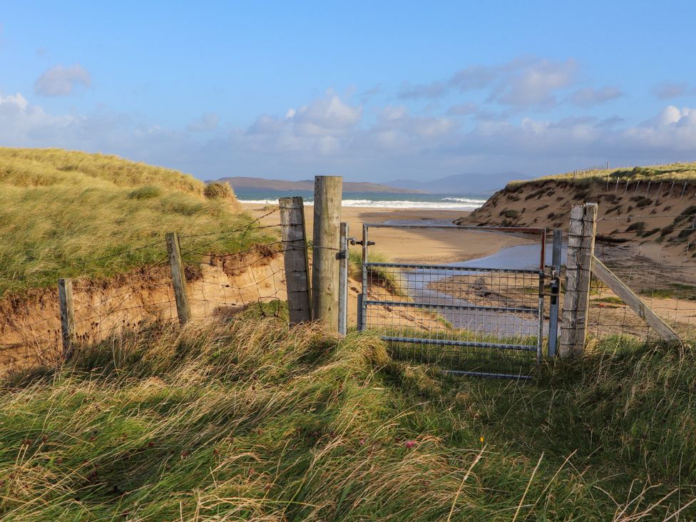 A gate and fence leading to a sandy beach at Otter Cottage Scarista near Leverburgh