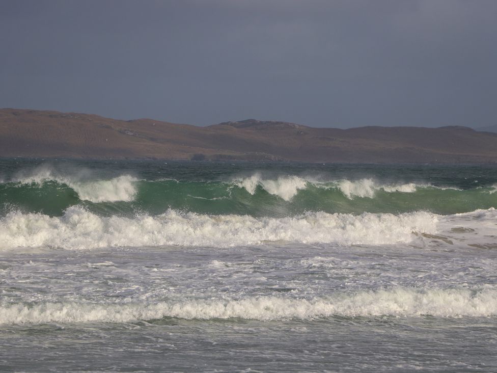 Waves breaking on a shore with distant land at Otter Cottage Scarista near Leverburgh