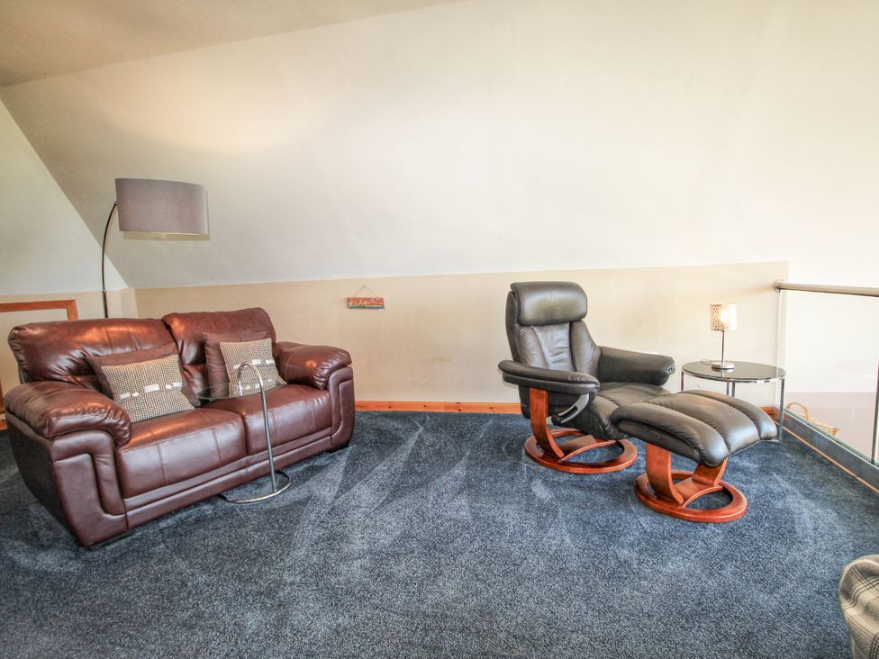 A living room with a sofa and a chair at Corncrake Cottage in Leverburgh