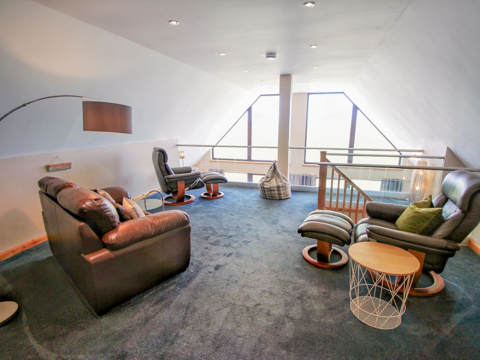A living room with furniture and large windows at Corncrake Cottage in Leverburgh