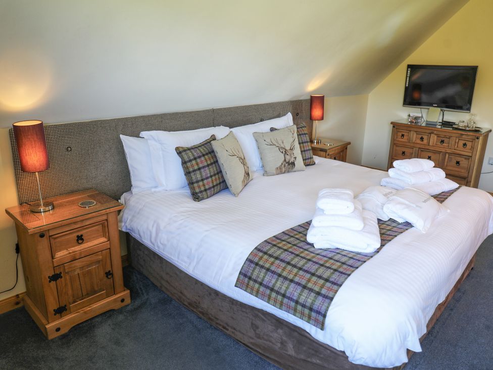 A bedroom with a double bed and television at Corncrake Cottage in Leverburgh