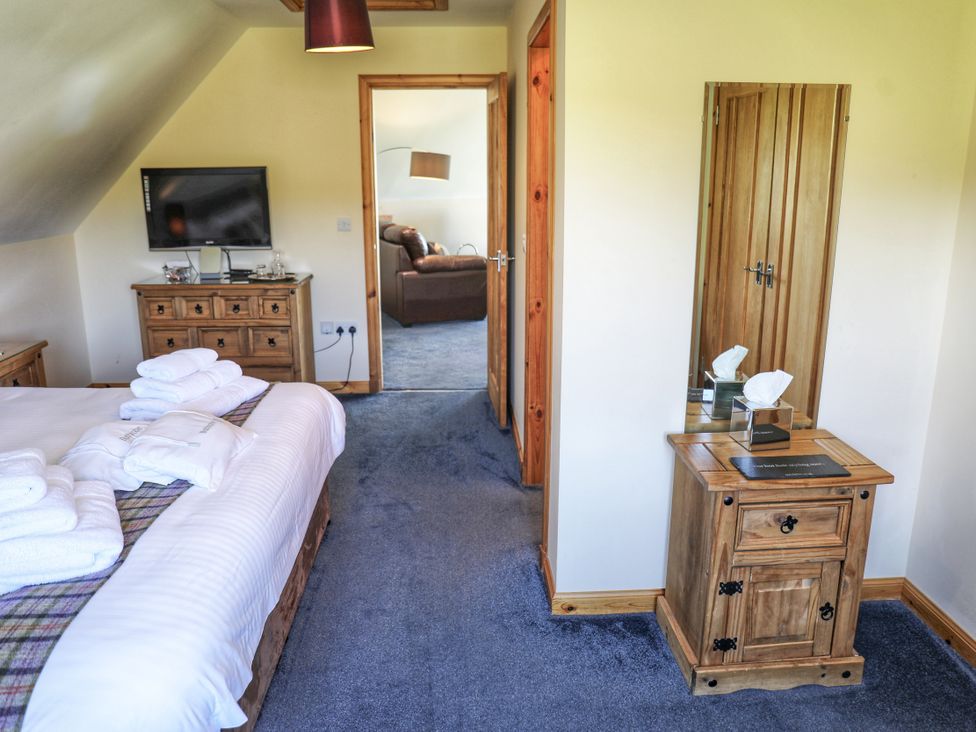 A bedroom with a bed, television and dresser at Corncrake Cottage in Leverburgh
