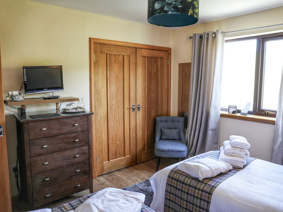 A bedroom with a TV and dresser at Corncrake Cottage in Leverburgh