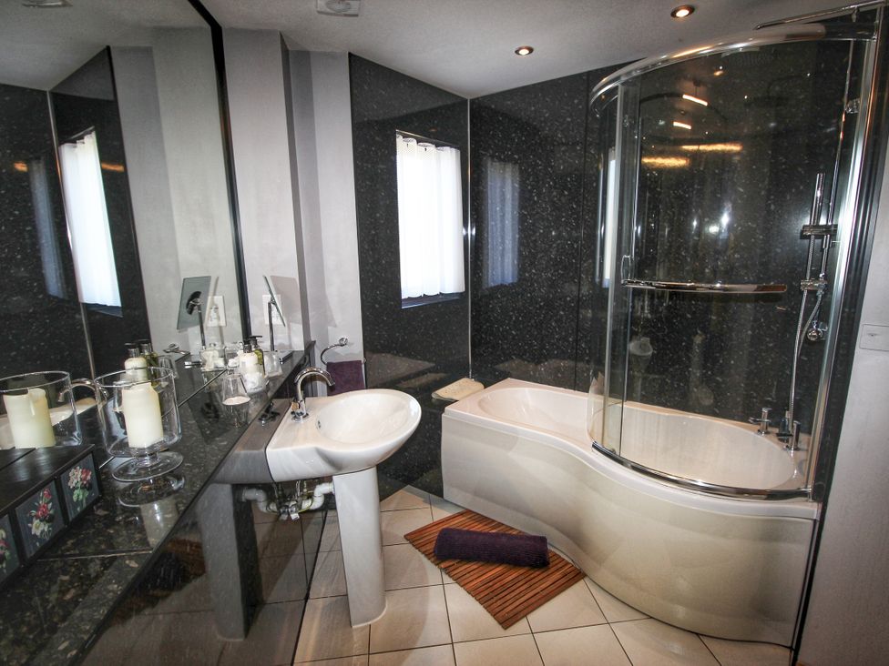 A bathroom with a sink, bathtub, and shower at Corncrake Cottage in Leverburgh