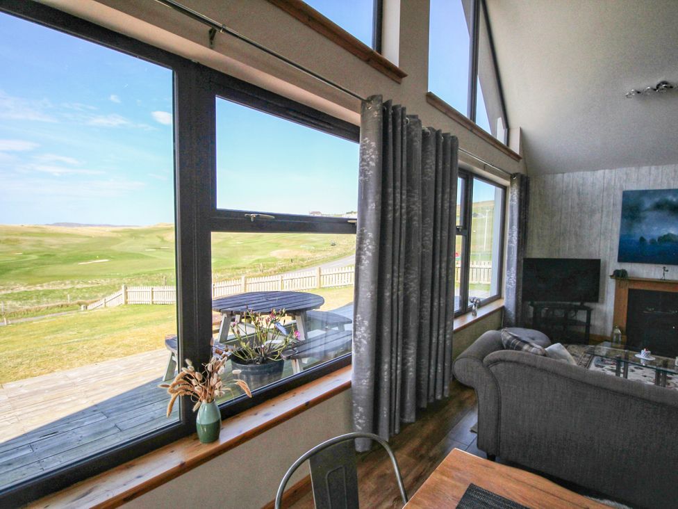 A living room with windows overlooking a scenic view at Corncrake Cottage in Leverburgh