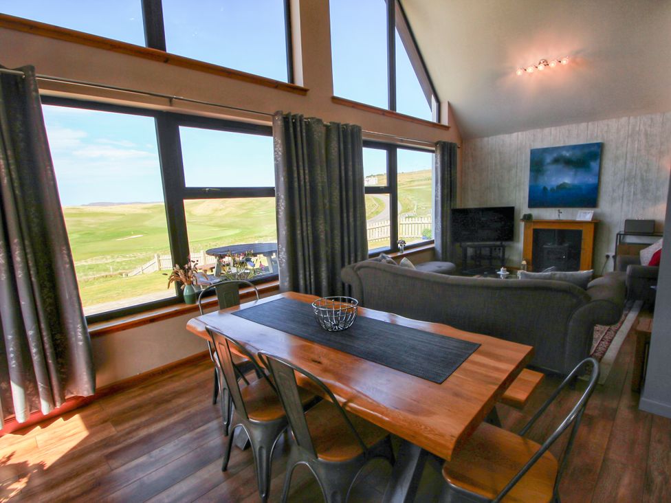 A living room with a dining table and sofa at Corncrake Cottage in Leverburgh