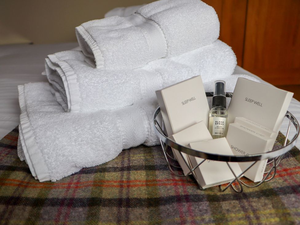 A stack of towels with toiletries in a basket at Corncrake Cottage in Leverburgh