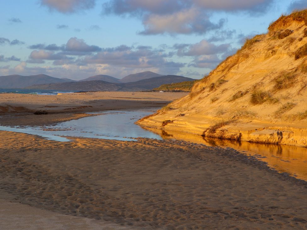 A beach with sand and water at Corncrake Cottage in Leverburgh