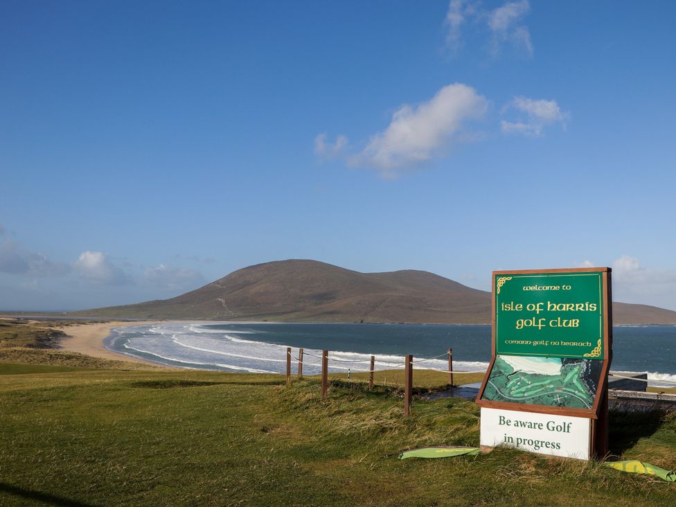 A golf club sign near a beach and mountain at Corncrake Cottage in Leverburgh