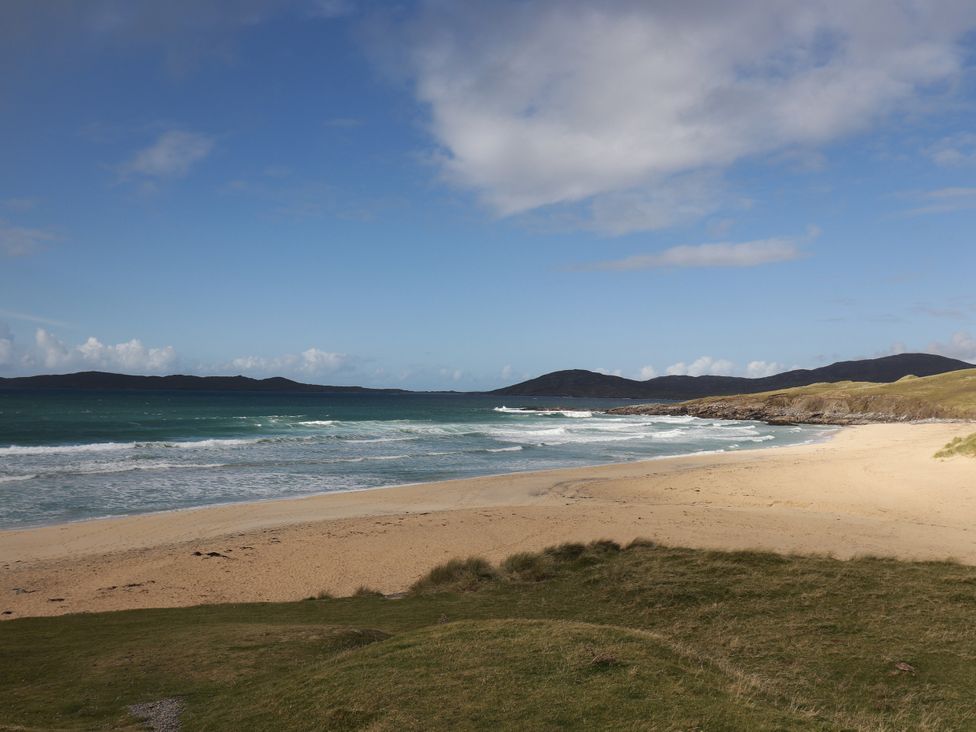 A beach with waves and sand at Corncrake Cottage in Leverburgh