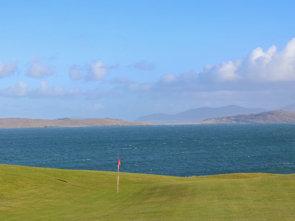 A golf course with a flag by the sea at Corncrake Cottage in Leverburgh