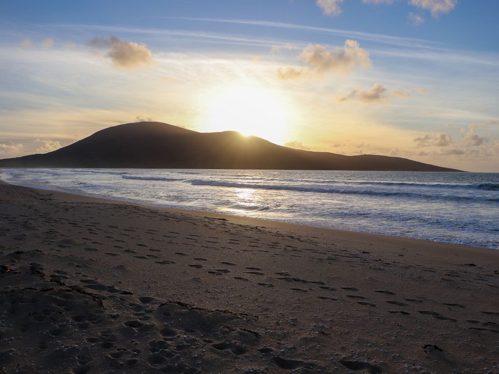 A beach with water and footprints at Corncrake Cottage Leverburgh