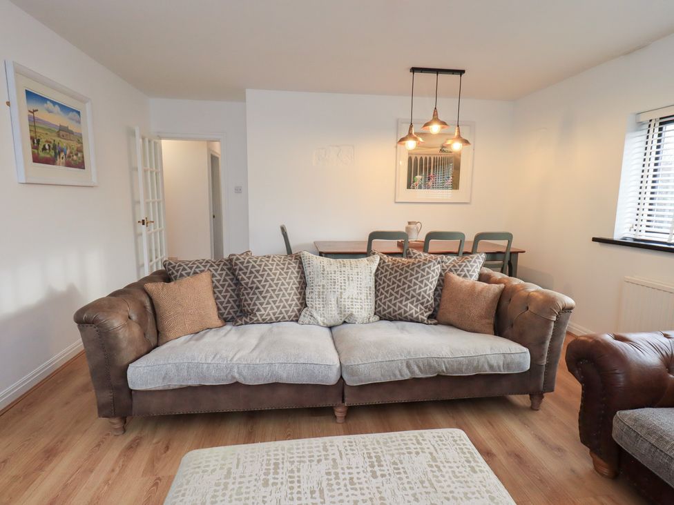 A living room with a sofa and dining table at Glen Lea in Giggleswick, Settle