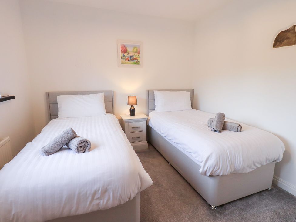 A bedroom with two beds and a nightstand at Glen Lea in Giggleswick, Settle