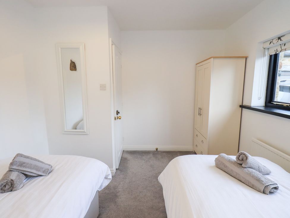 A bedroom with two beds and a wardrobe at Glen Lea in Giggleswick, Settle