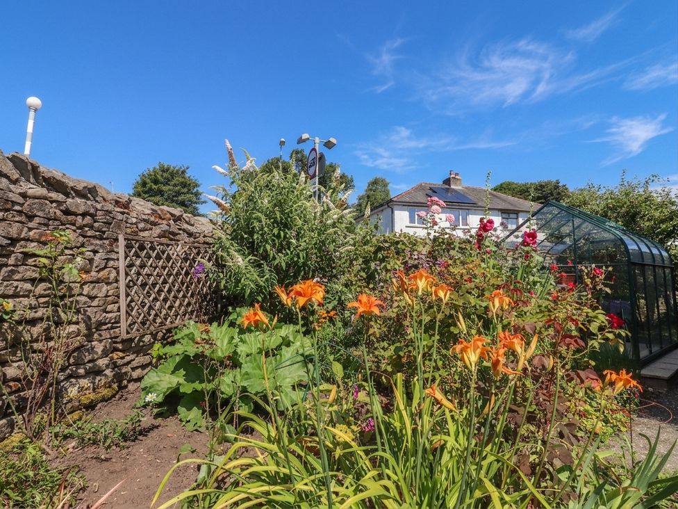 A garden with flowers and a greenhouse at Glen Lea in Giggleswick, Settle