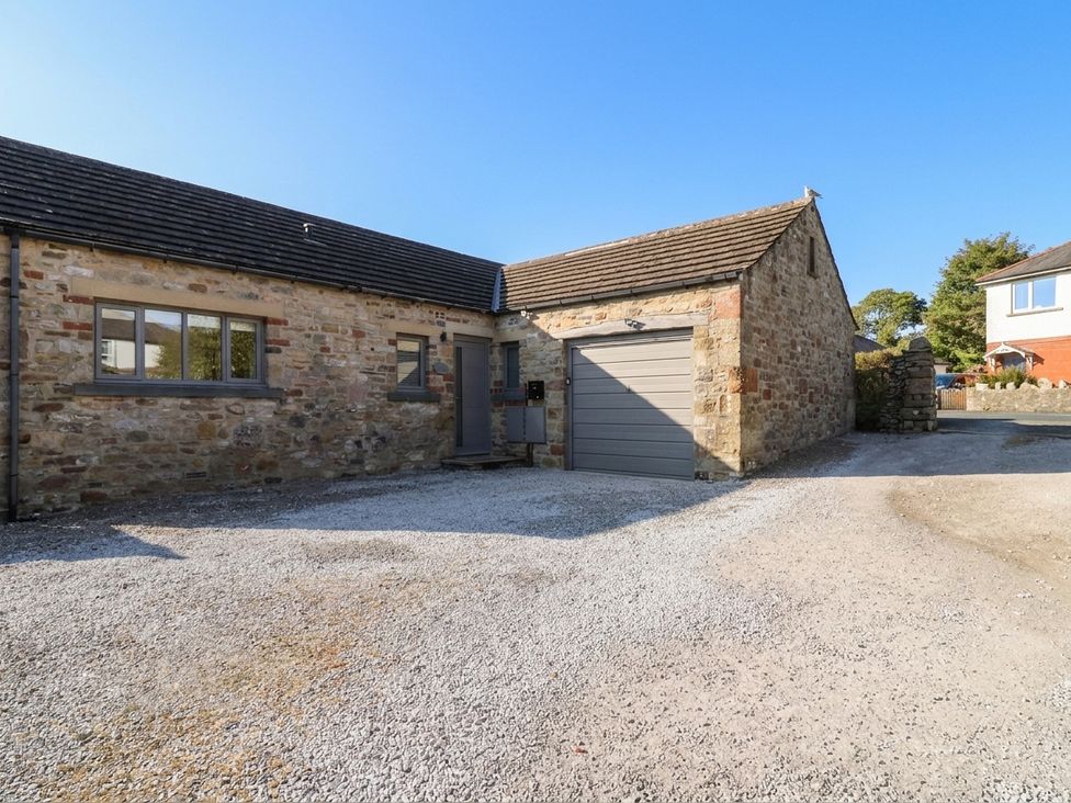A stone building with a garage and gravel driveway at Glen Lea in Giggleswick, Settle