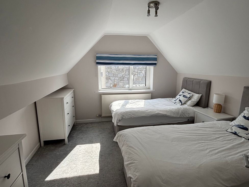 A bedroom with two beds and a dresser at Swn Y Mor in Benllech