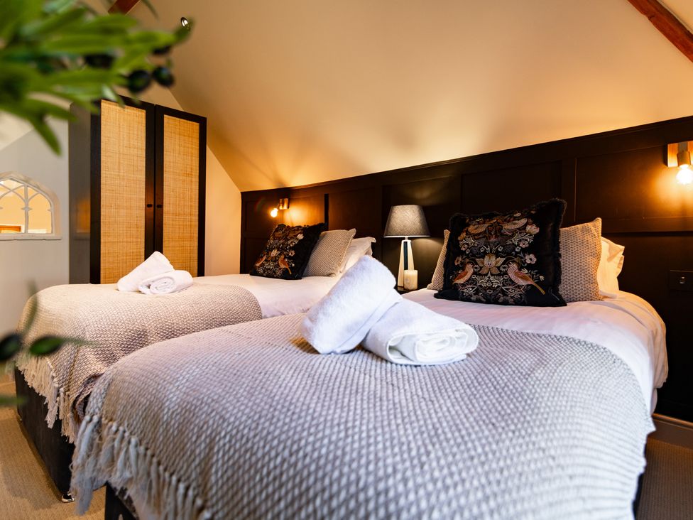 A bedroom with two beds and a wardrobe at Dovecote in East Langdon near St Margaret's At Cliffe