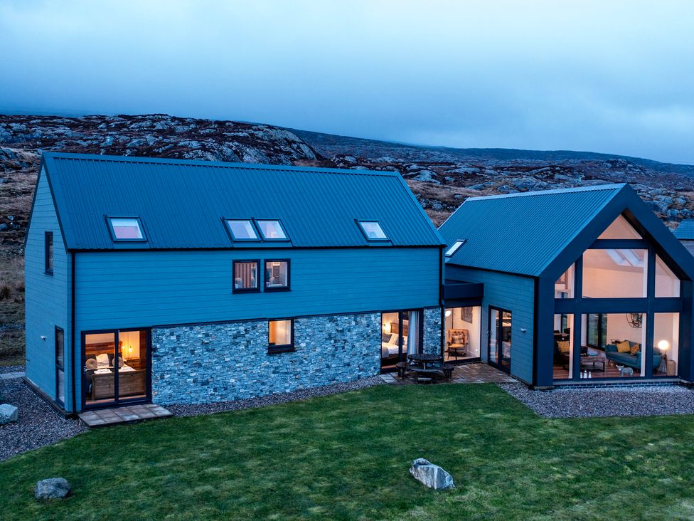 An exterior view of a house with a stone wall and large windows at Taigh Rona in Luskentyre Isle Of Harris