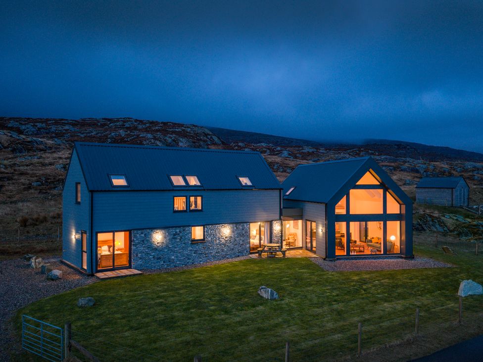 A house in a rural area with lights on at Taigh Rona, Luskentyre Isle Of Harris