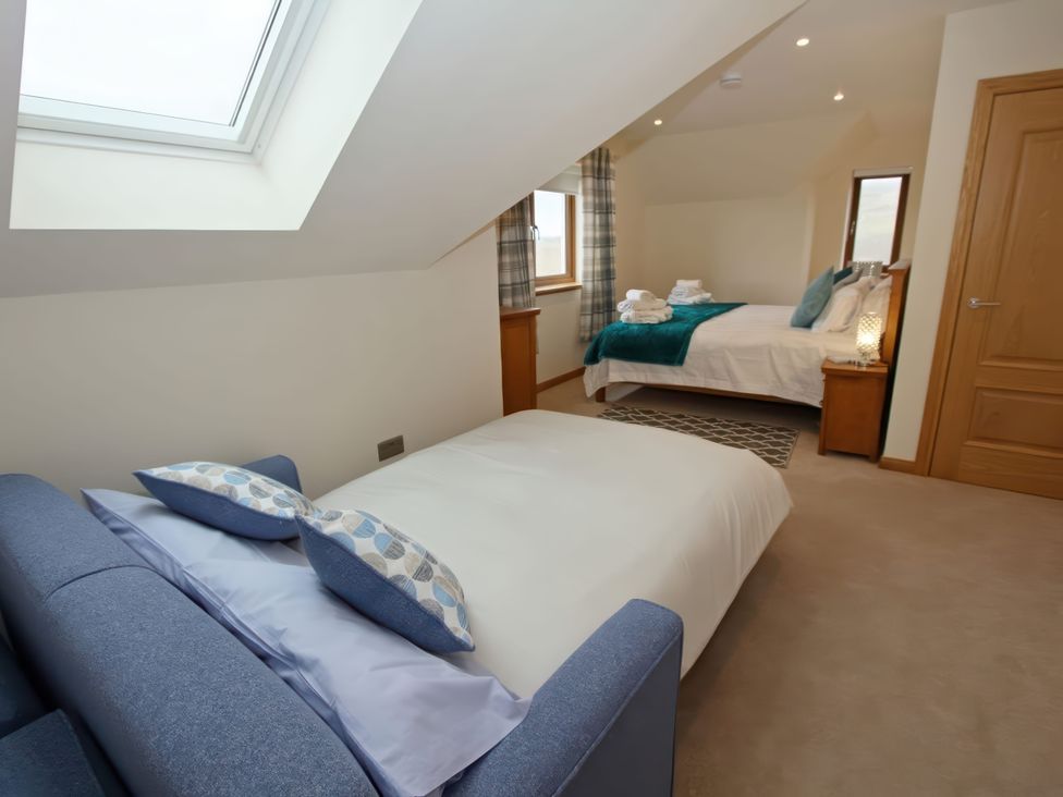A bedroom with beds and a sofa bed at Falls Cottage Uig