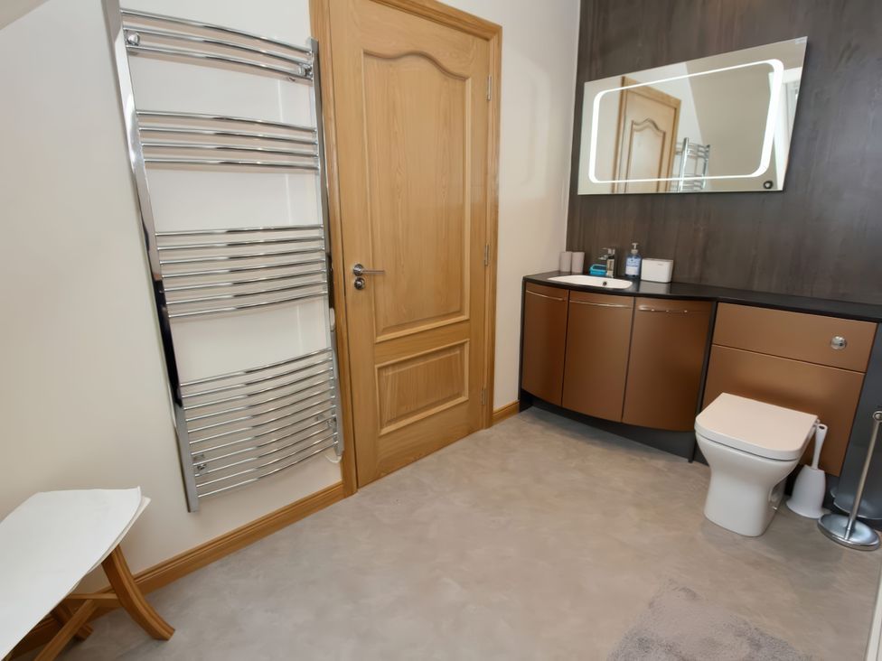 A bathroom with towel rail, sink, mirror, and toilet at Falls Cottage in Uig