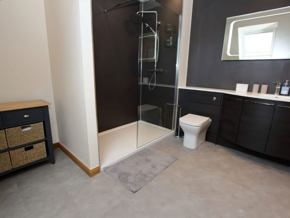 A bathroom with a shower, toilet and storage at Falls Cottage in Uig