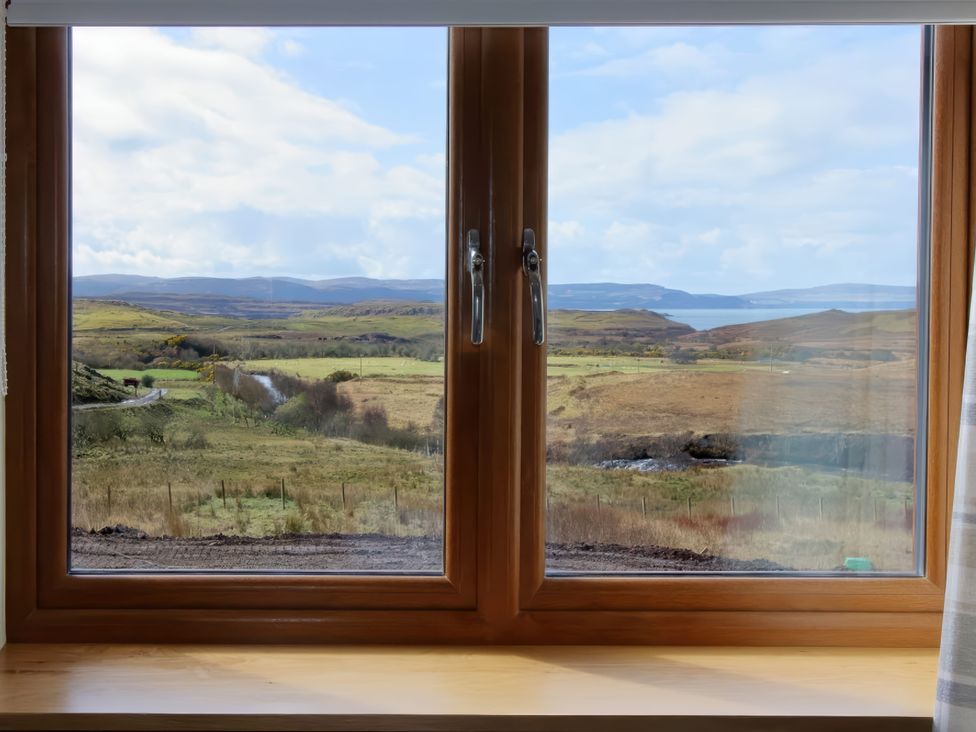 A view from a window showing hills and a road at Falls Cottage in Uig