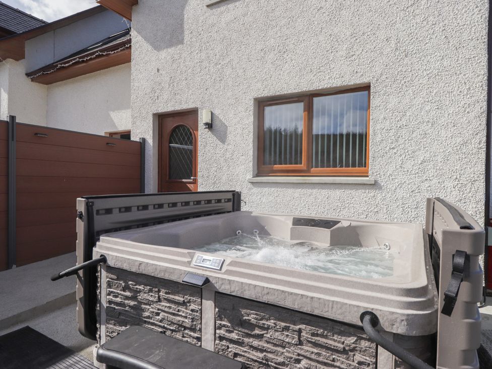 An outdoor hot tub near a wall and window at Falls Cottage Uig