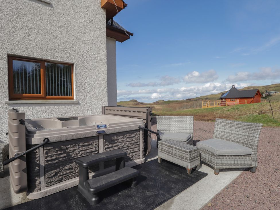 An outdoor area with a hot tub and seating at Falls Cottage Uig