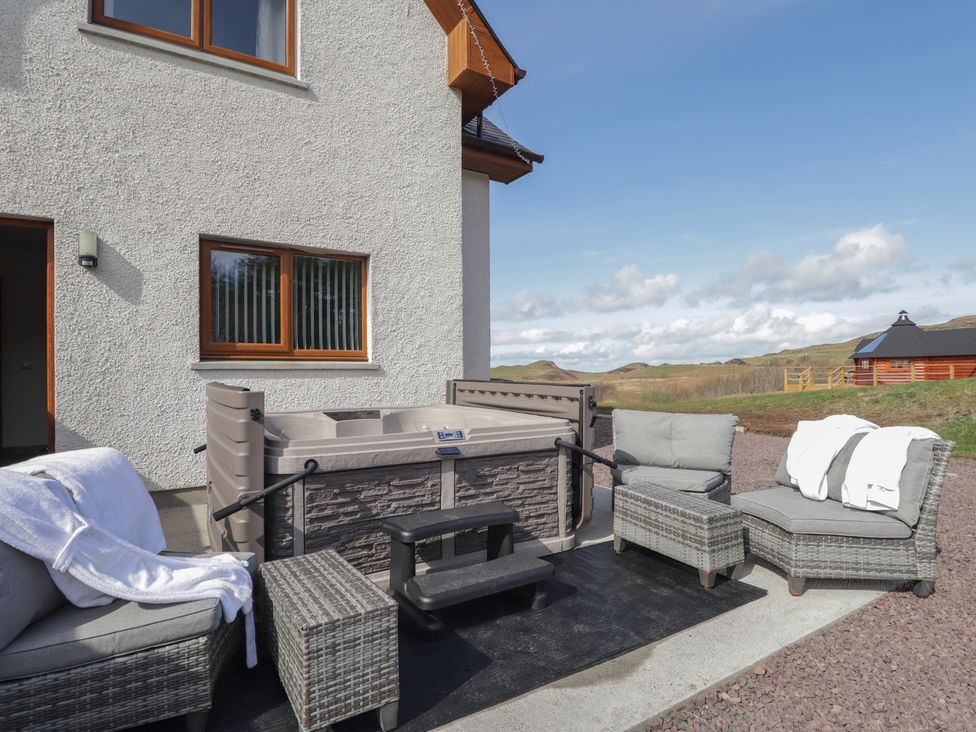 An outdoor seating area with a hot tub and sofa at Falls Cottage Uig