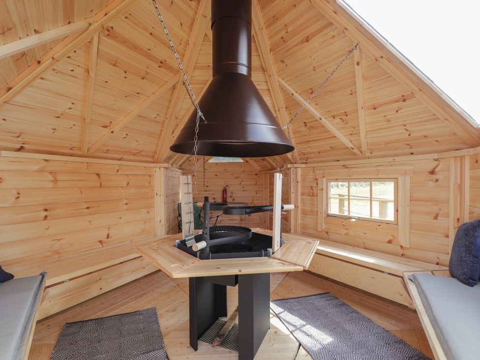 A summer house with a grill and benches at Falls Cottage in Uig