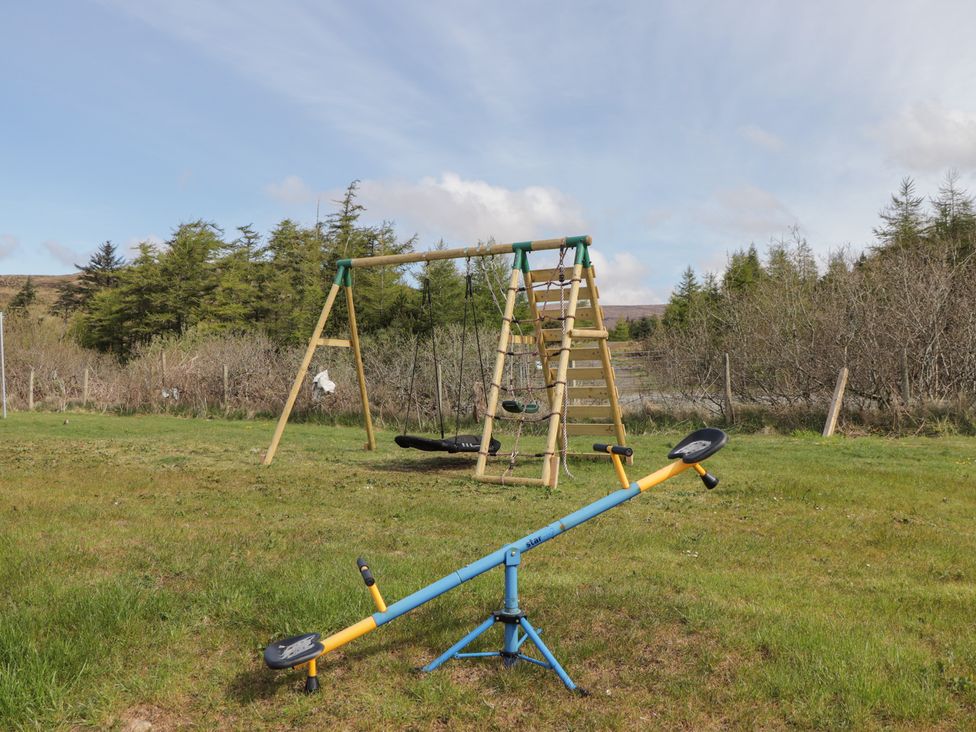 A playground with a swing set and seesaw at Falls Cottage in Uig