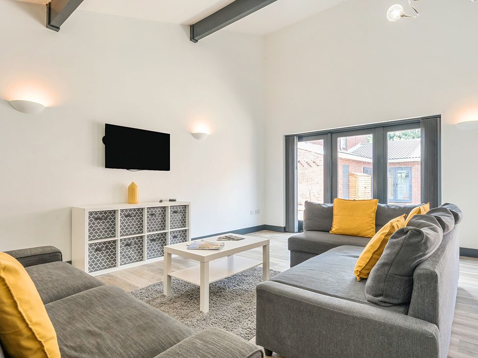 A living room with a sofa, coffee table and television at The Cottage in Wimborne Minster