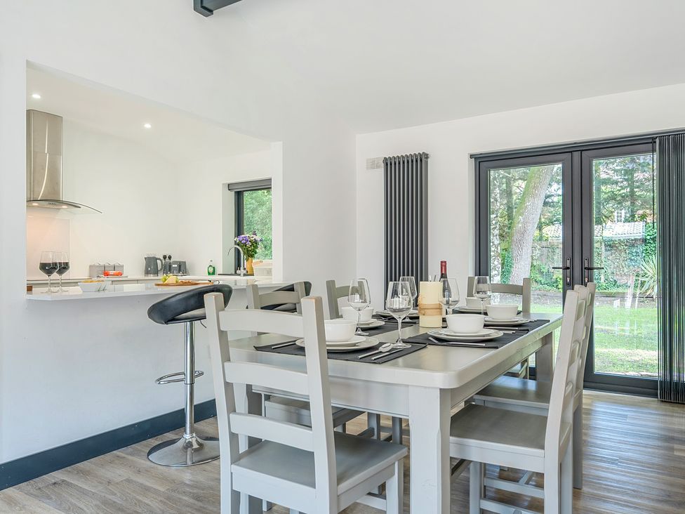 A dining area featuring a table with chairs and a bar stool at The Cottage in Wimborne Minster