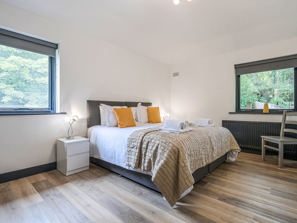 A bedroom with a bed and windows at The Cottage in Wimborne Minster