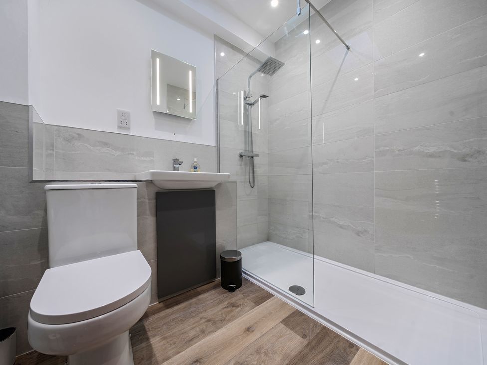 A bathroom with a shower, toilet, sink, and mirror at The Cottage in Wimborne Minster