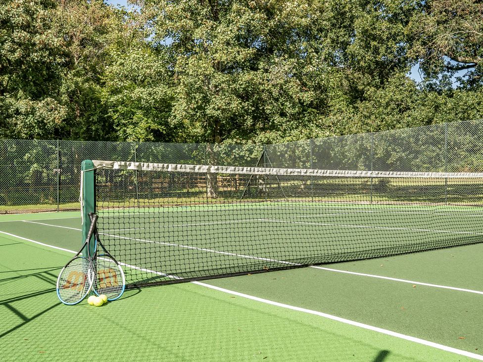 A tennis court with rackets and balls at The Cottage in Wimborne Minster