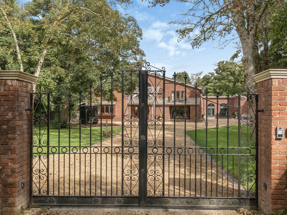 A gated entrance leading to a house and driveway at The Cottage in Wimborne Minster