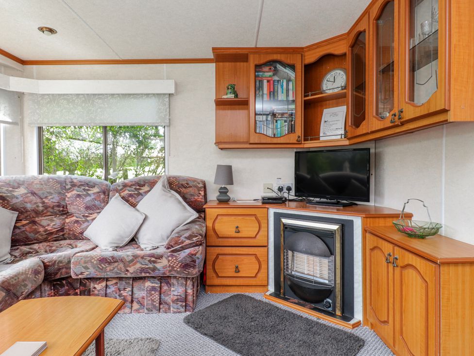 A living room with a sofa and television at Fron Dderw Caravan Llanfairynghornwy near Llanfechell