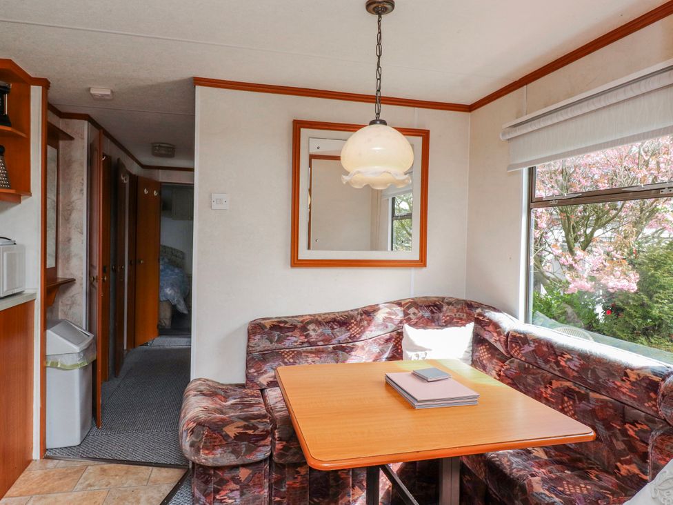 A dining area with a table and sofa at Fron Dderw Caravan in Llanfairynghornwy near Llanfechell