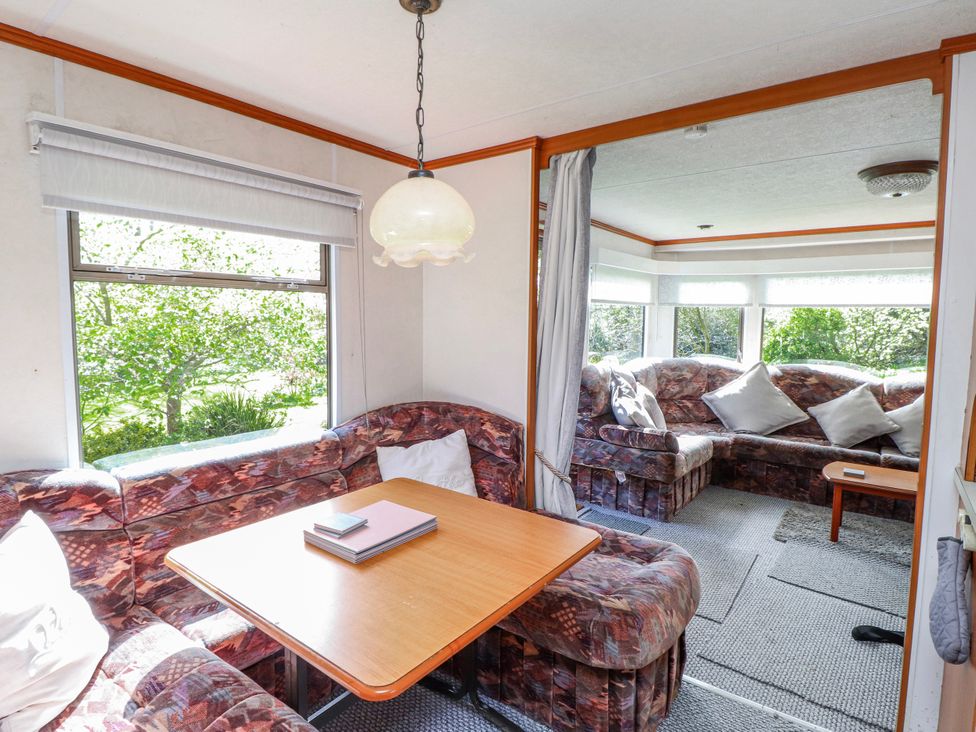 A living room with a table and sofas at Fron Dderw Caravan in Llanfairynghornwy near Llanfechell