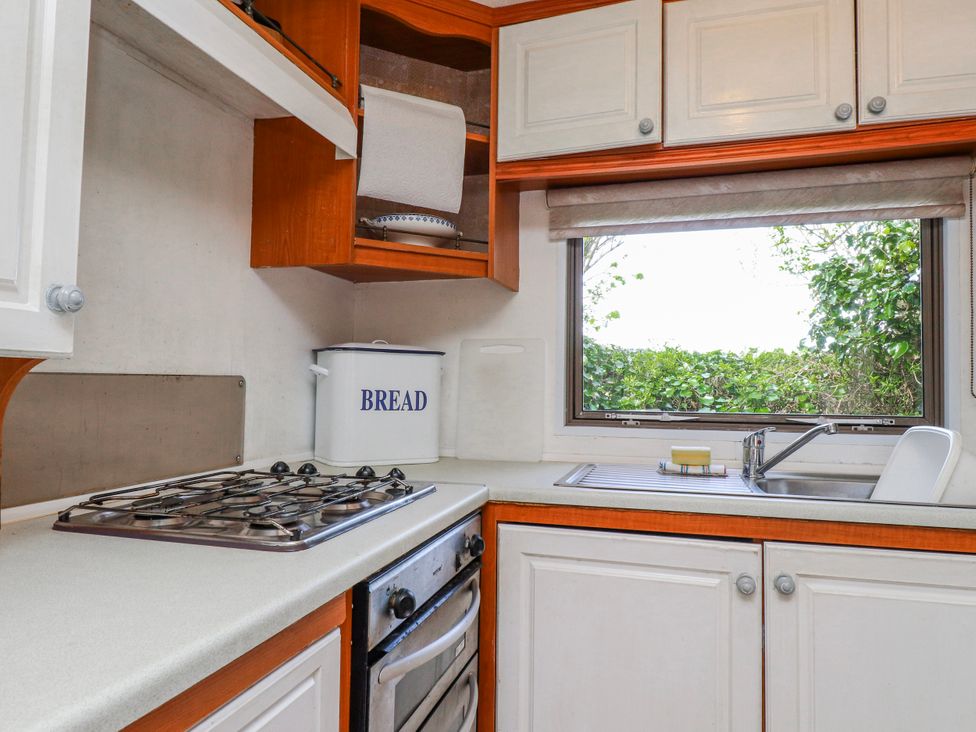 A kitchen with a stove and sink at Fron Dderw Caravan in Llanfairynghornwy near Llanfechell