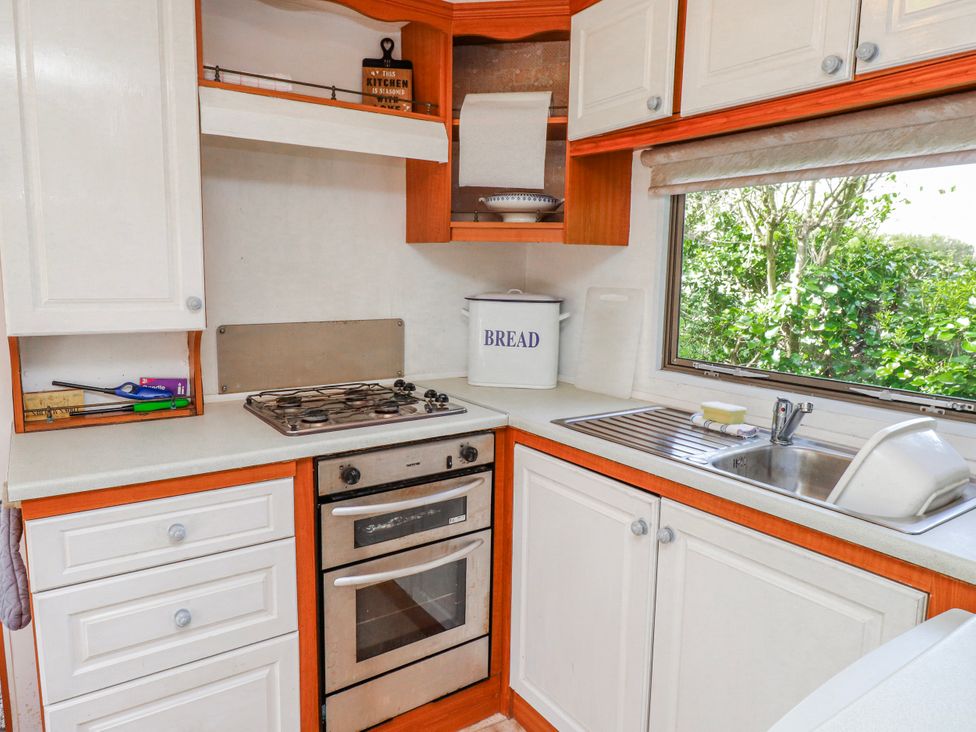 A kitchen with cabinets and appliances at Fron Dderw Caravan in Llanfairynghornwy near Llanfechell