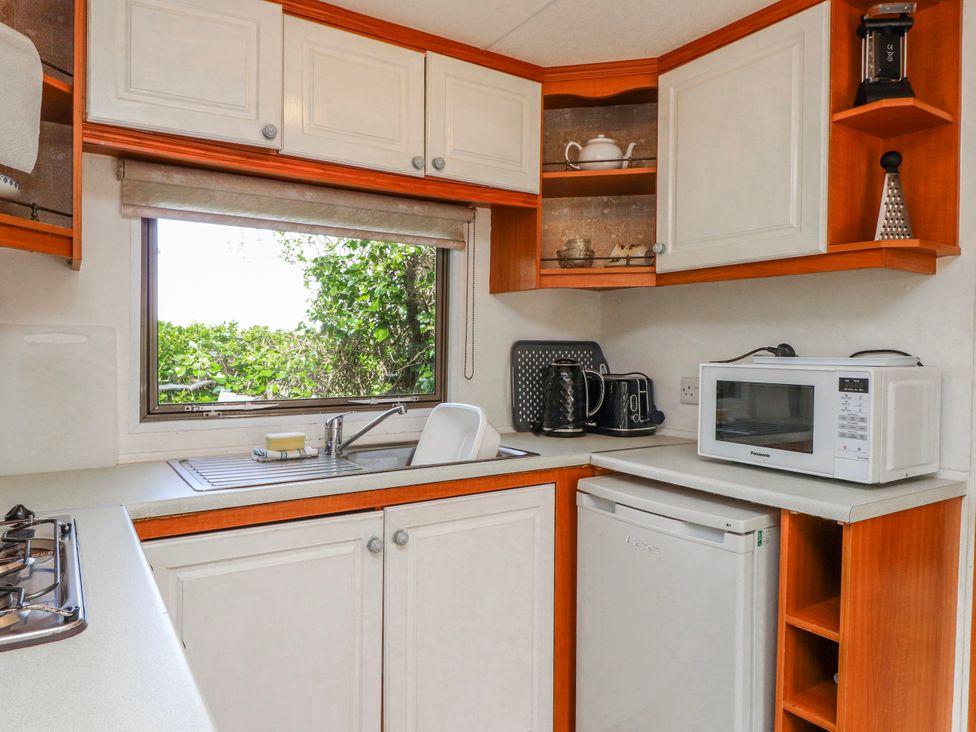 A kitchen with sink and appliances at Fron Dderw Caravan Llanfairynghornwy near Llanfechell