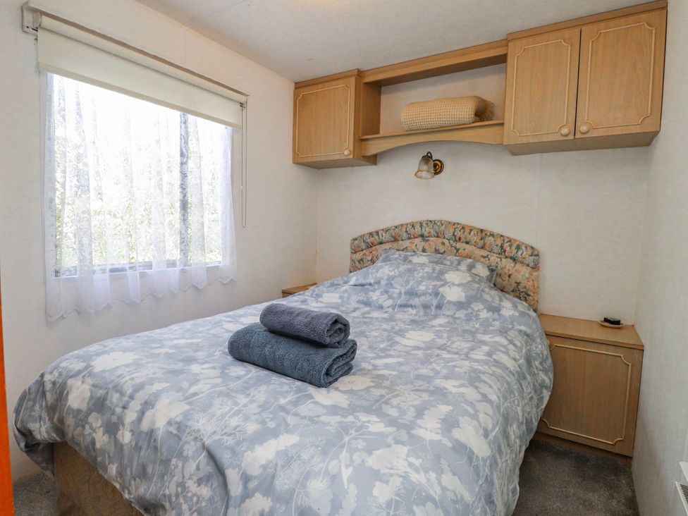 A bedroom with a bed and towels at Fron Dderw Caravan Llanfairynghornwy near Llanfechell