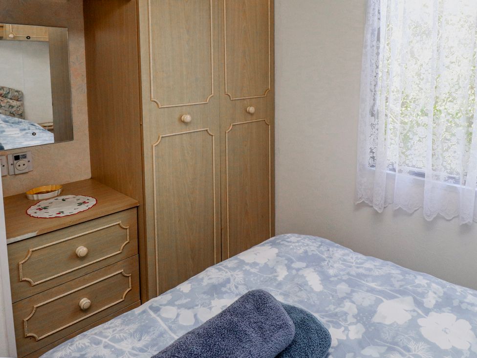 A bedroom with a bed and wardrobe at Fron Dderw Caravan Llanfairynghornwy near Llanfechell